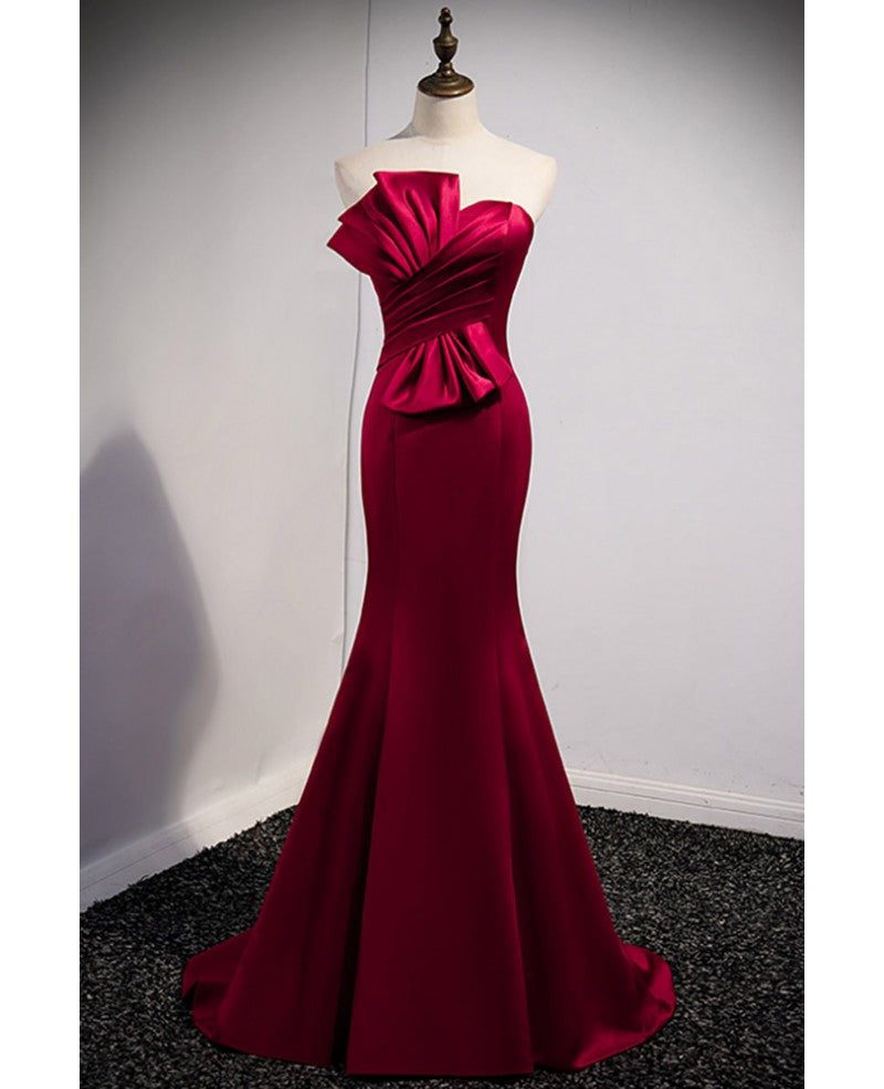 Un abito da ballo rosso vino nobile e minimalista, senza maniche, con spalle scoperte, spalline senza spalline e schiena color rosso vino e abito da sera a sirena lungo fino a terra.